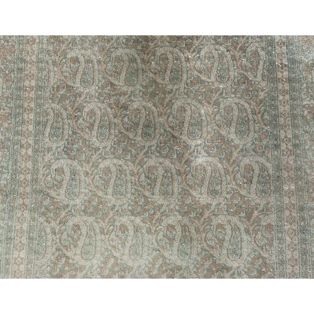 A hand-knotted wool antique Persian Tabriz rug dating back to 1930. The main field features an all over paisley pattern...