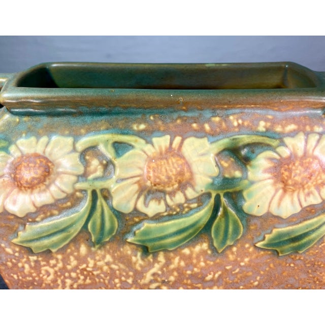 Introduced by Roseville Pottery in 1928. Dahlrose is decorated with a daisy-type, yellow flower and green leaves on a...