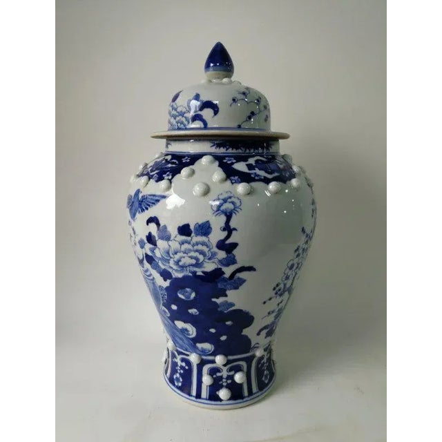 This blue and white porcelain jar is adorned with hand painted blooming flowers and flying birds. Antiquing process...