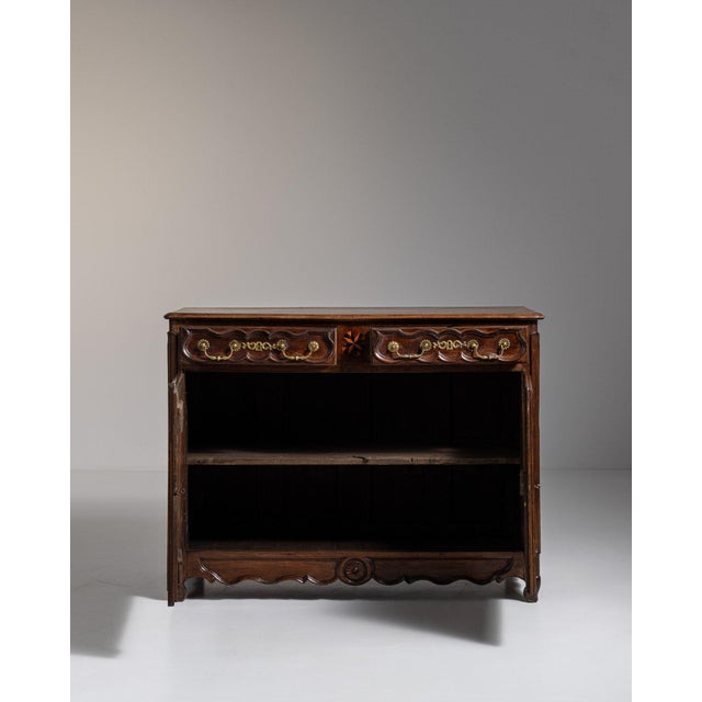 This 1800s Louis XV ornate buffet with brass hardware from France is made in dark carved wood with two doors, shaped...