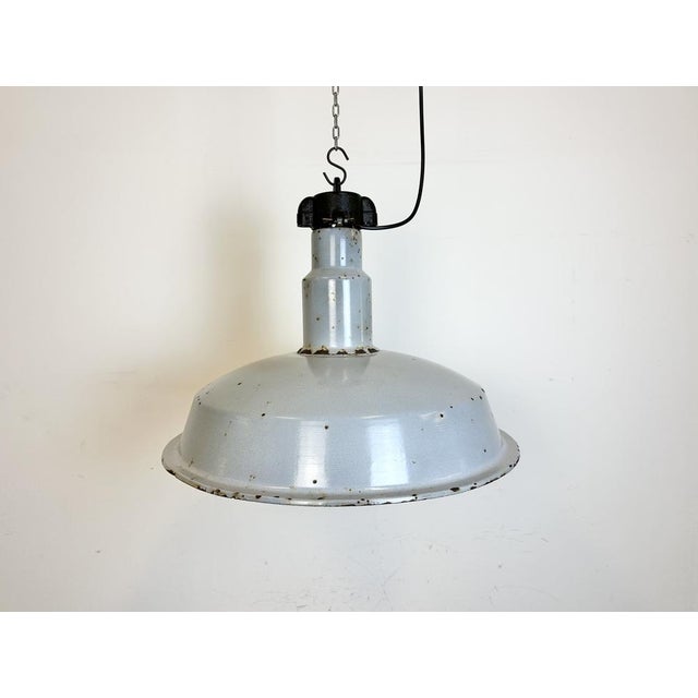 This industrial lamp was made in former Czechoslovakia during the 1950s. It features grey enamel shade with white...