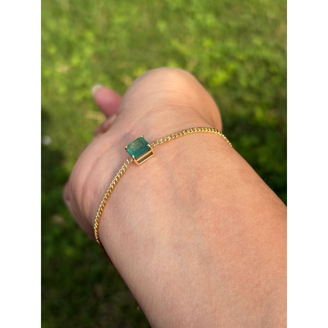 This station bracelet features a 1.46 carat Asscher-cut natural emerald set in 14K yellow gold. The emerald measures...
