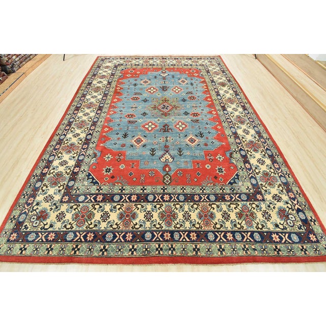 This traditional tribal geometric Caucasian Kazak rug is hand-knotted with an all-wool pile on a cotton foundation. This...