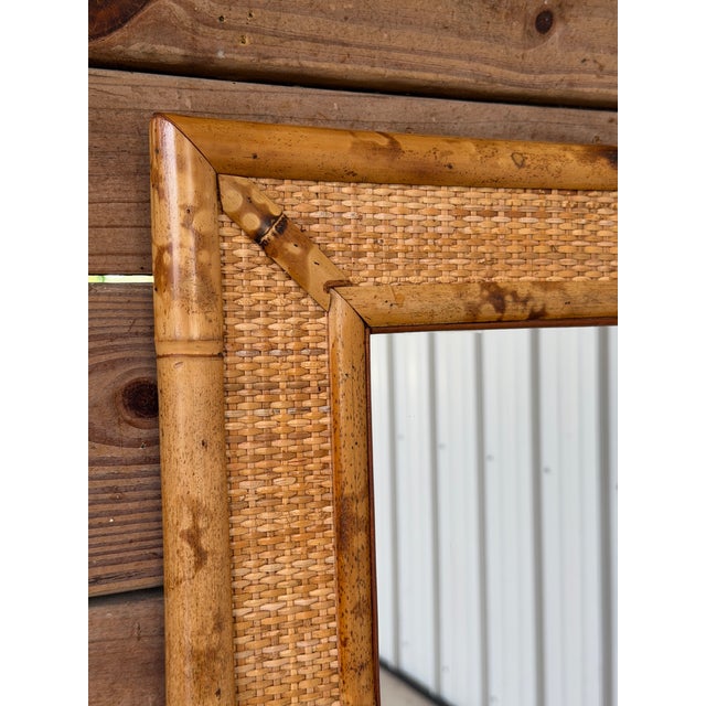 A beautifully refinished vintage wall mirror featuring a classic tortoise bamboo frame with woven rattan inset panels. The...