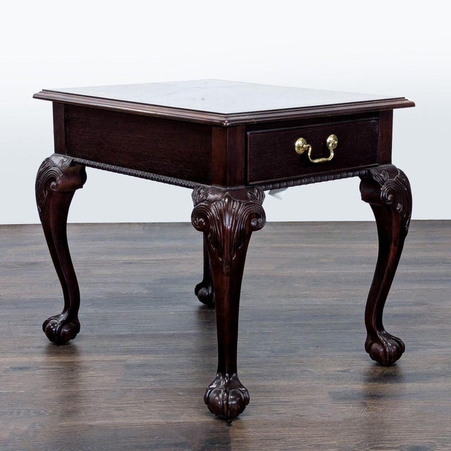 Chippendale style end table made of mahogany wood with flame top. It features a single dovetailed joined drawer adorned...