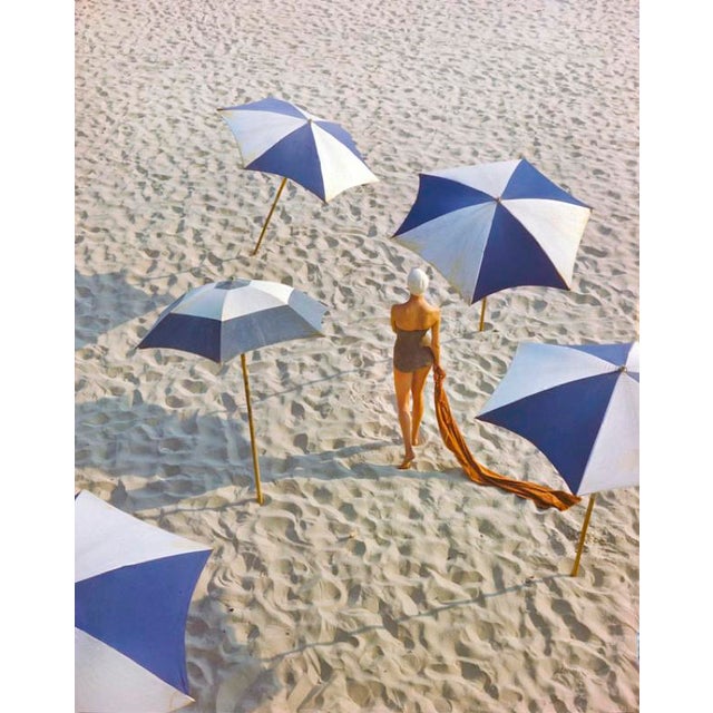 Girl On The Beach by Toni Frissell Beachwear fashion shoot featuring a model on a sandy beach wearing a swimsuit and a...