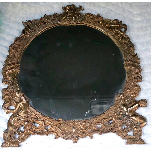 A rare 19th Century Cast Bronze Hanging Mirror With Figural Decorations featuring detailed cherubs and cupids along the...