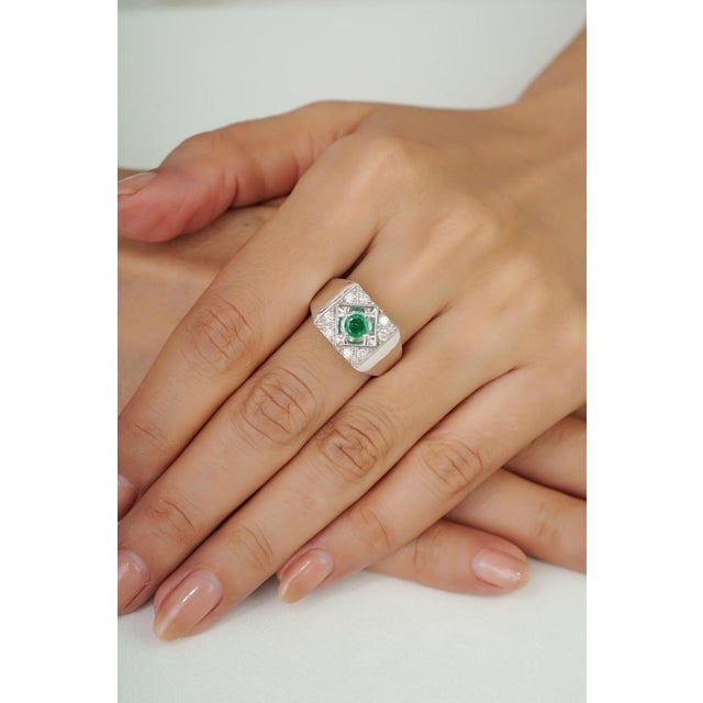 Crafted in 925 sterling silver, this bold emerald signet ring features a vibrant 5 mm round-cut emerald (0.55 carats)...
