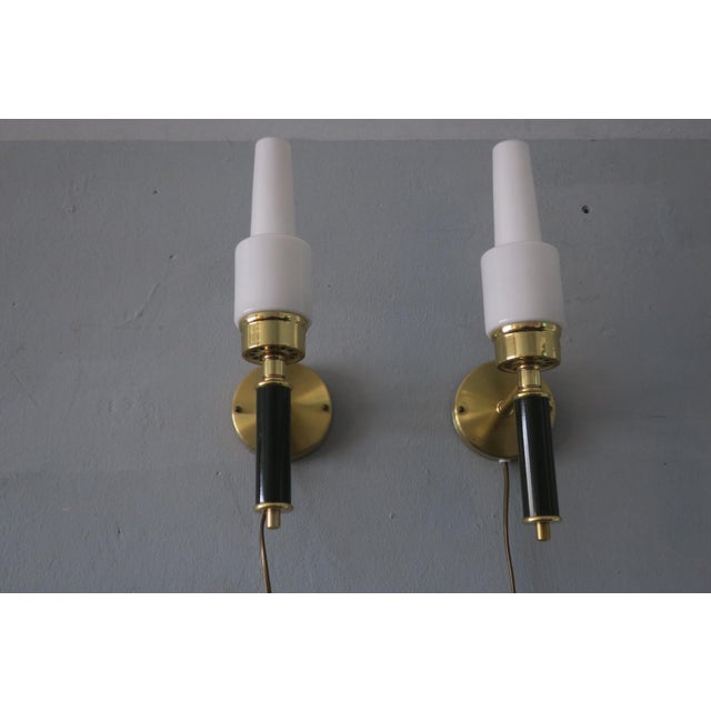 Elegant pair of brass and black laquered metal wall lights with opal glass shades designed by c e fors for ewo varnamo,...