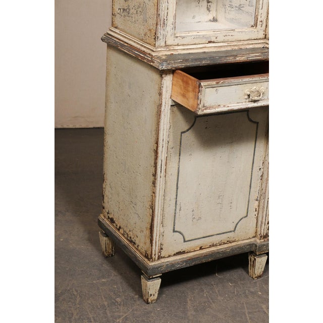 A French tall display and storage cabinet from the early 20th century. This antique painted-wood cabinet from France has a...