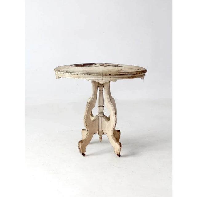 This antique accent table captures the charm of Eastlake Victorian design with its oval top, carved apron, and sculptural...
