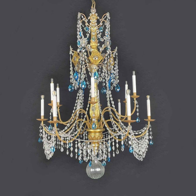 A Genoese twelve-light gilded Empire chandelier, composed of a turned, carved, and gilded wooden shaft and twelve gilded...