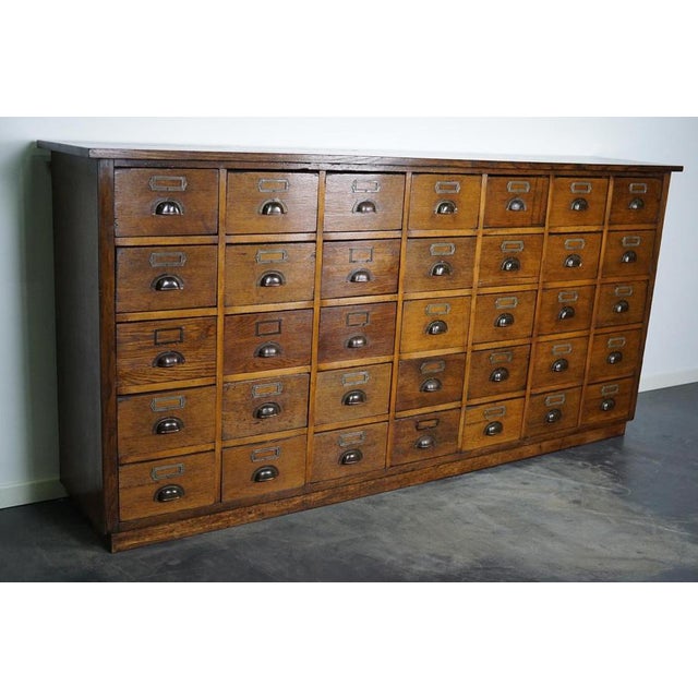 This apothecary cabinet was made circa 1930s in Germany. It features 35 decent sized drawers with cup handles and name...