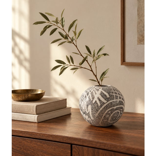 A small art glass vase with a rounded silhouette and striking black-and-white decoration. Fine speckling creates a richly...