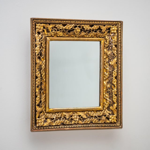 Rectangular giltwood wall mirror with applied stucco decoration of grape clusters and foliage, framed by a cymatium frieze...