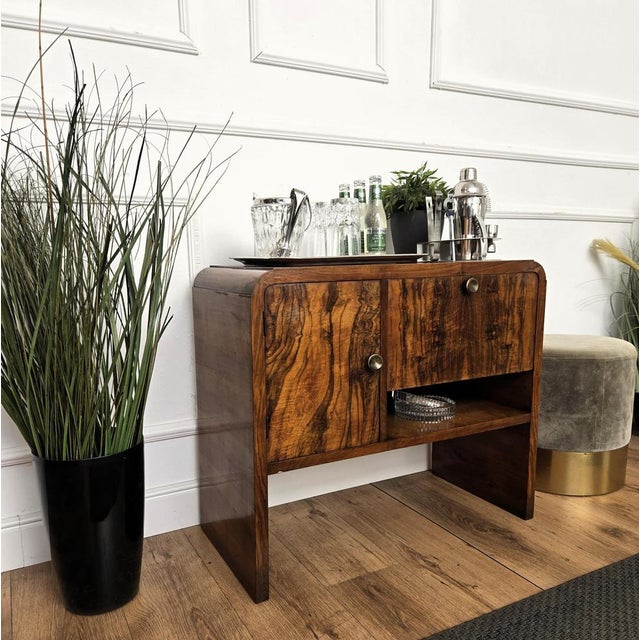 Very elegant Italian side table in typical Art Deco shape and materials with its beautiful wood, two openings and the...