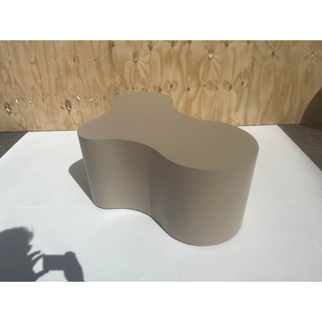 One Freeform Coffee Table, constructed of plywood and wood. Taupe lacquer finish. Table has ball casters. Table is not...