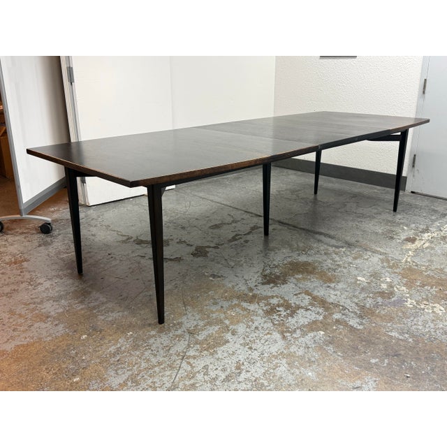 Design Plus Gallery presents a Mid Century Modern Styled Walnut Wood Dining Room Table. The table has a bow shaped with a...