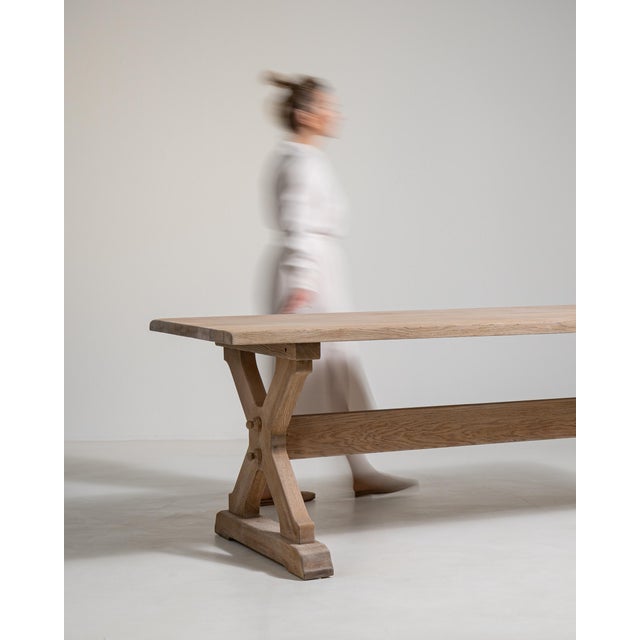 A classic trestle dining table showcasing solid oak construction and enduring craftsmanship. The form remains timeless and...