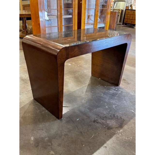 This handsome walnut Italian writing table exudes mid-century charm with its Art Deco style. The glass top adds a...