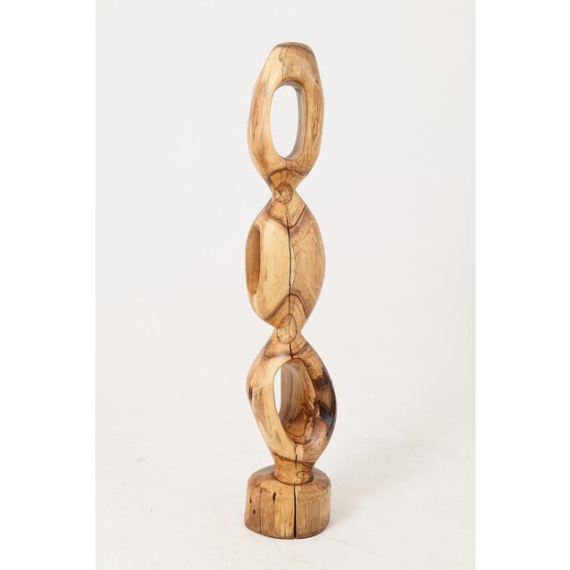 Carved from a single solid log, the form rises through a series of open, pierced voids that give the piece a lightness...