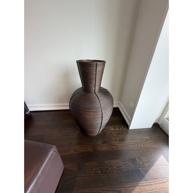 A stunning wooden woven floor vase featuring a tightly wrapped, ribbed exterior that creates a dynamic spiral texture...
