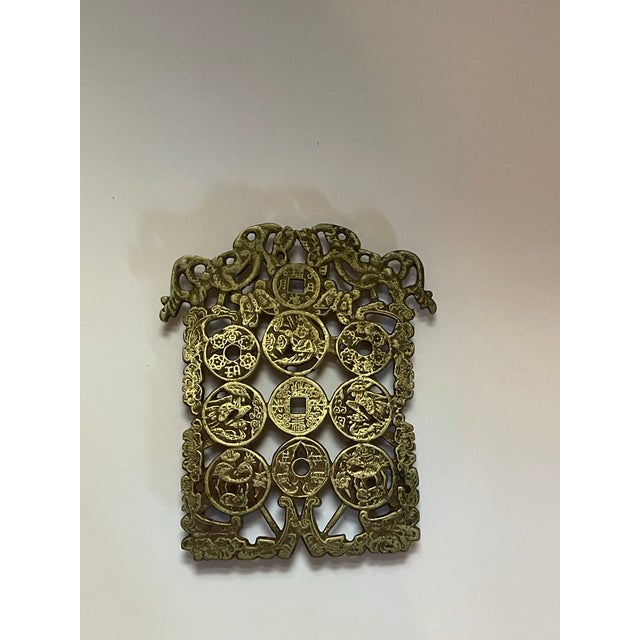 An interesting early 20th century metal trivet featuring a number of natural themed designs set on a pattern of coins.