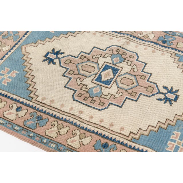 This is a vintage Turkish Oushak rug from the Mid 20th Century. The piece was hand-knotted.