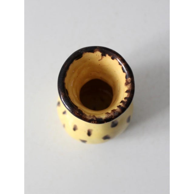 A vintage handmade studio pottery vase featuring a warm buttery yellow glaze accented by dark brown drip detailing and...