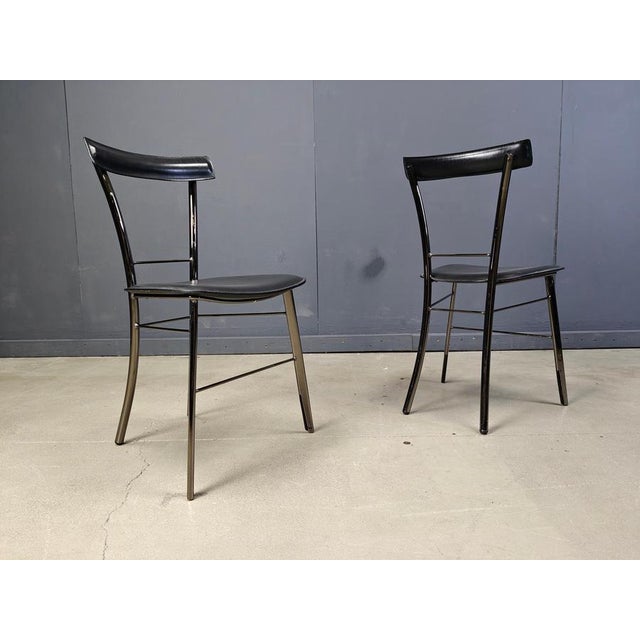 Set of 4 italian dining chairs consisting of black metal frames with black leather upholstery both on the seats and...