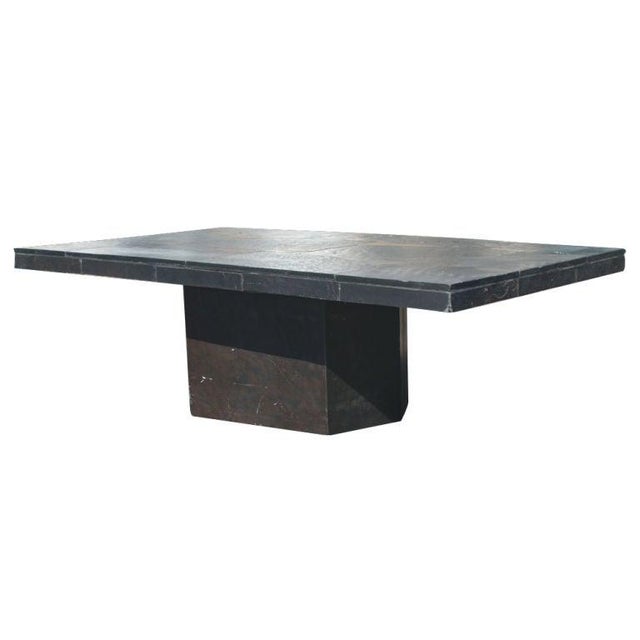 A mid-century modern coffee table with a black slate base and geometric top.