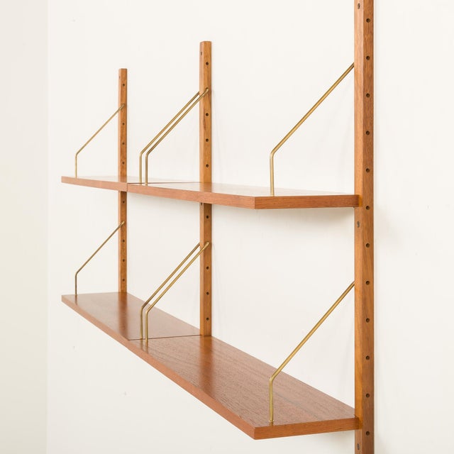 This minimalist danish mid-century teak shelving unit is a modular system with an attractive, airy aesthetic. It is...