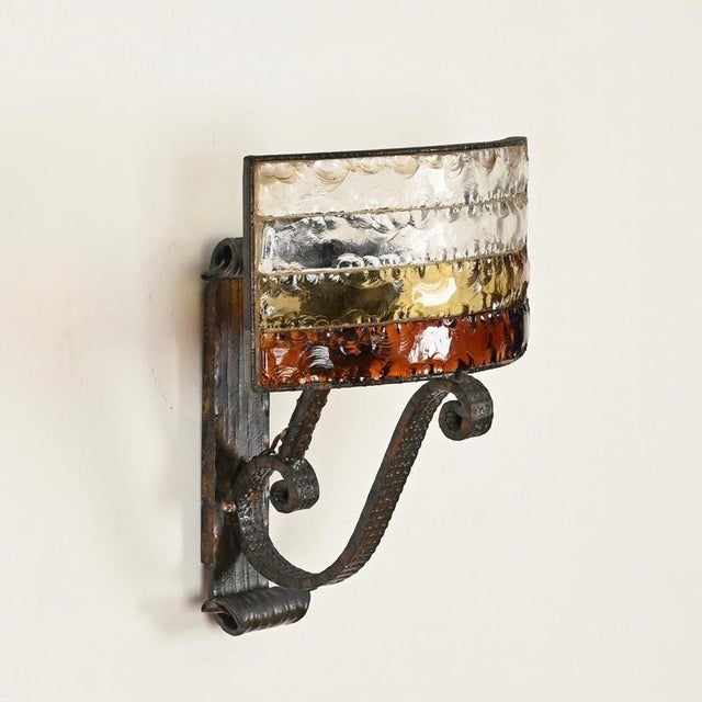 Stunning and unique large brutalist-style wall sconce, crafted from wrought iron and sculpted colored glass. This...