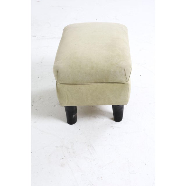 This piece is a suede upholstered ottoman with distinctive "ox horn" legs that curve outwards that provide stability and a...