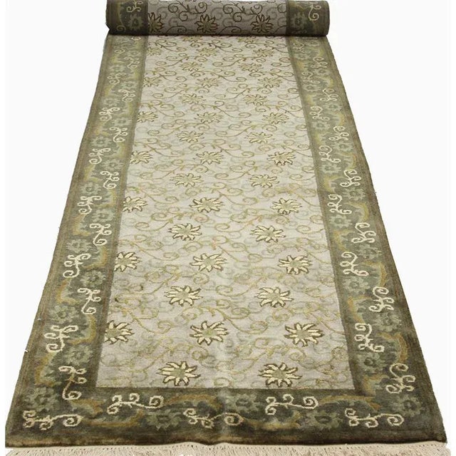 Handwoven wool and silk Indian rug featuring Tibetan design with a mushroom colored field and olive border accented in...
