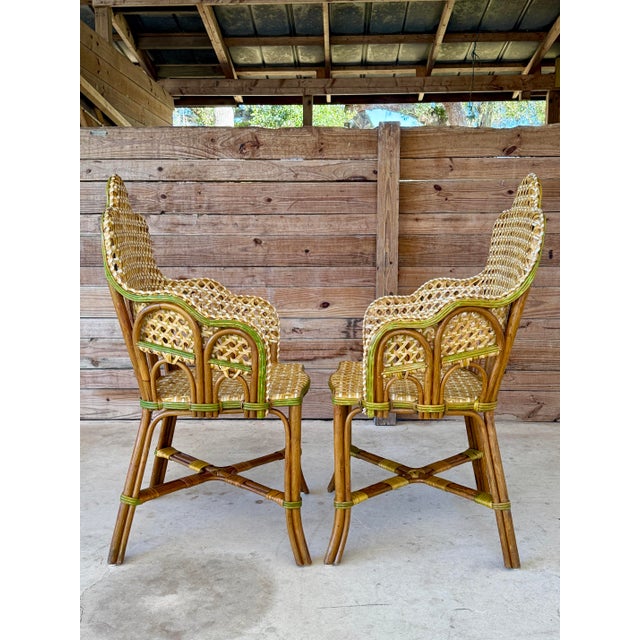 Exceptional pair of vintage French-style rattan bistro side arm chairs featuring beautifully sculpted silhouettes and...