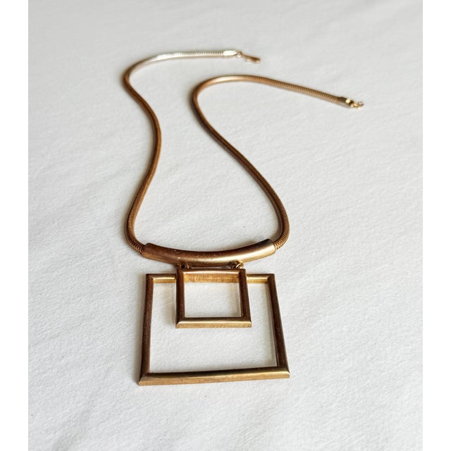 Vintage 1970s modernist statement necklace featuring two interlocking open square pendants suspended from a curved...