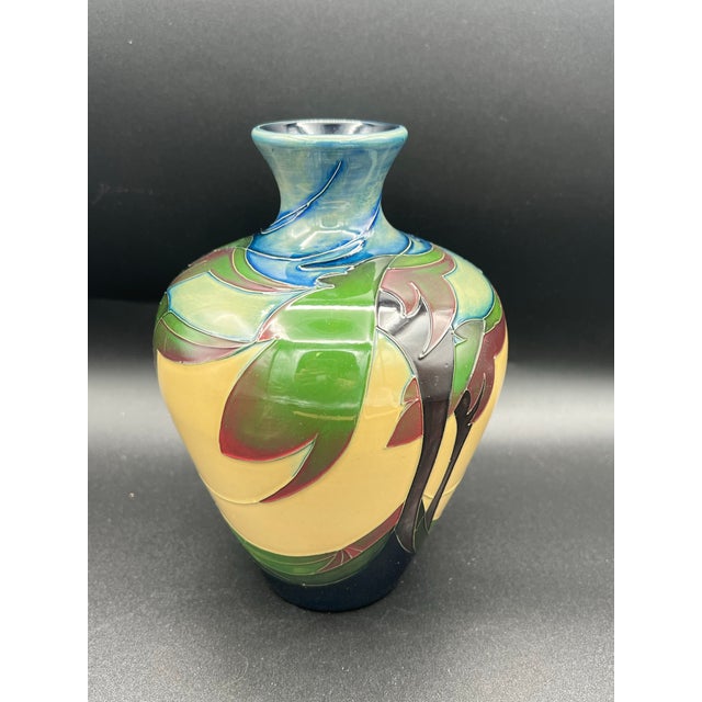 The Moorcroft Pottery Vase from 2010 is a 7" tall clay vase featuring a beautiful multicolor palm trees pattern,...