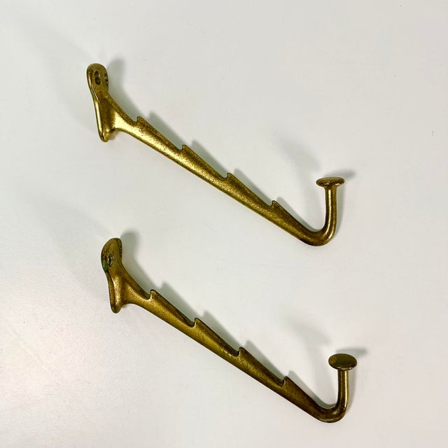 These are a great find. From the 1940s we have a pair of metal wall mounted hooks that feature four stacking notches and a...