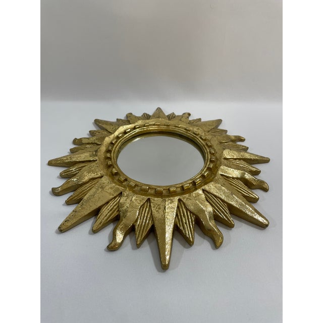 A very bright and stunning gold gilded 12.5" Sunburst Wall Mirror, circa 1990s. This fabulous mirror features a notched...