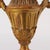 A decorative pair of carved and gilded wooden urns in the neoclassical style, originally used as lamp bases. The urn forms...