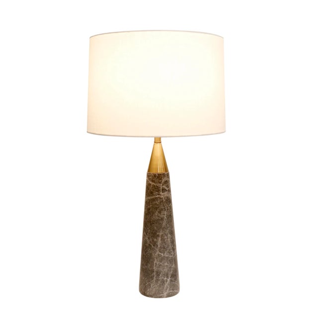 The Radiance table lamp features a spire-shaped body crafted from natural gray marble, accented with a gold finish and...