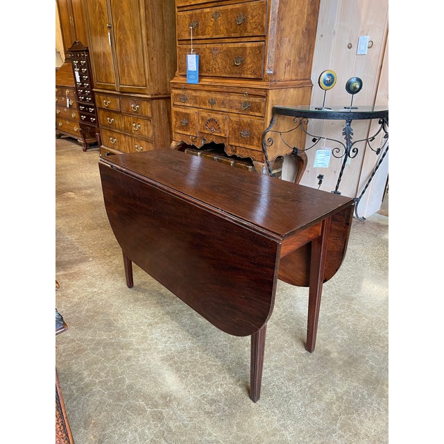 This vintage mahogany drop-leaf table showcases classic craftsmanship and timeless practicality. The rectangular center is...