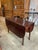 This vintage mahogany drop-leaf table showcases classic craftsmanship and timeless practicality. The rectangular center is...