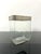 Flower vase composed of a transparent glass container with a rectangular base and a decorative upper edge in satin metal....