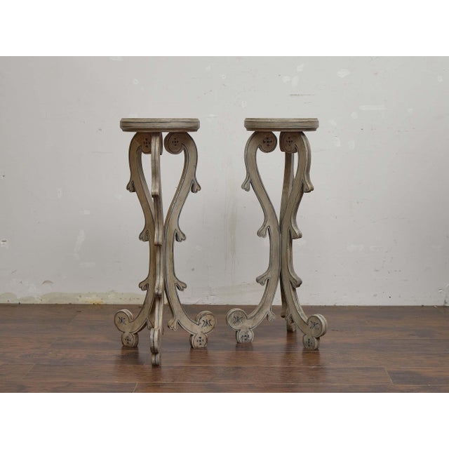 A pair of English painted pedestals from circa 1900, designed with elegant scroll-sawn supports and a light decorative...
