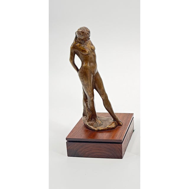 This graceful bronze figurine captures a serene, intimate moment as the figure holds a towel with both hands behind her...