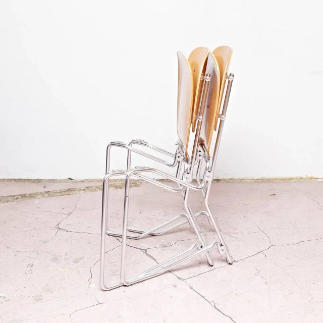 This stackable Aluflex chair features an aluminum frame as well as a seat and backrest in wood.