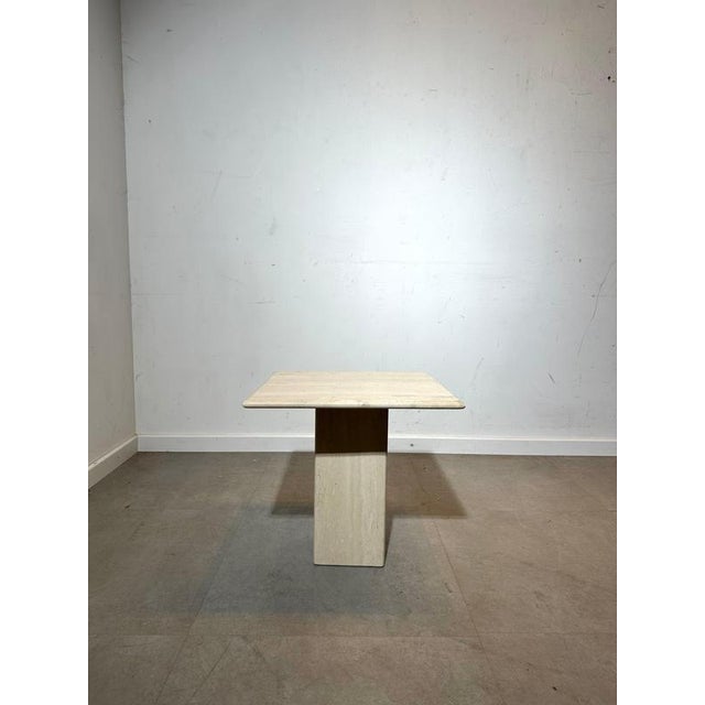 A beautifully sculptural vintage travertine side table featuring a square top and a solid pedestal base. Its clean...