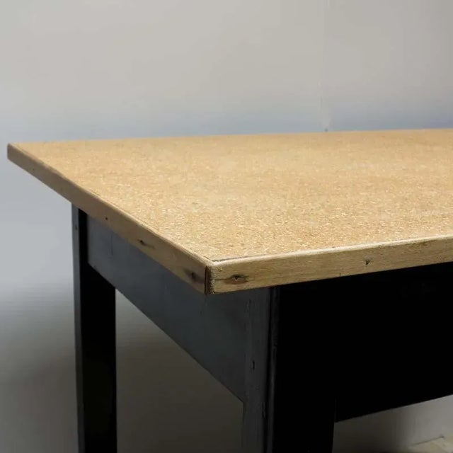 This wooden table with four legs and a drawer has a painted black structure, and a drawer in red.